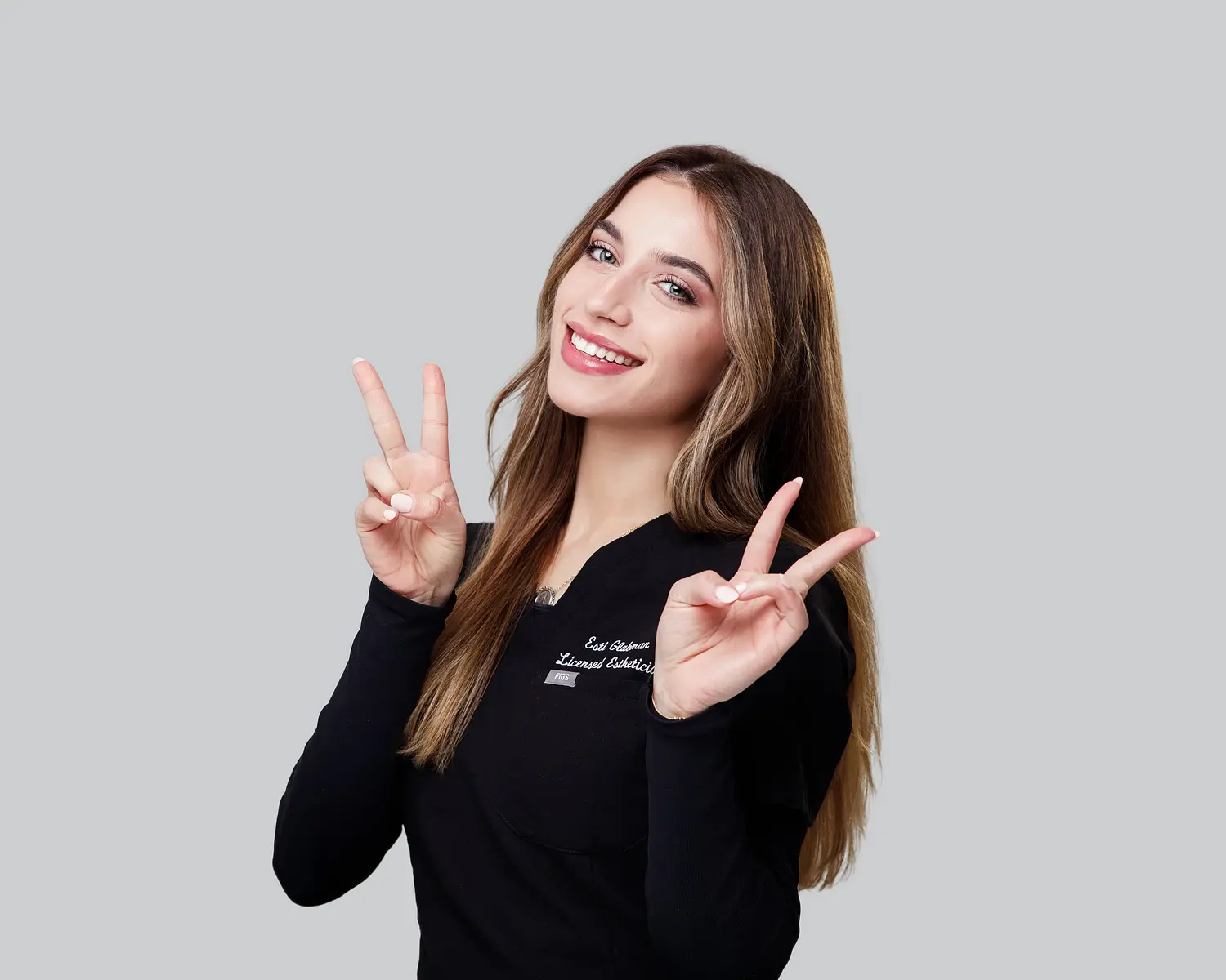 Glow Aesthetics Team Member smiling and holding up two fingers